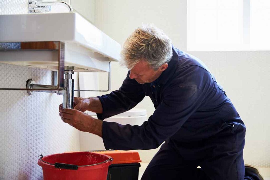 Plumber fixing a sink covered by his plumbers insurance policy